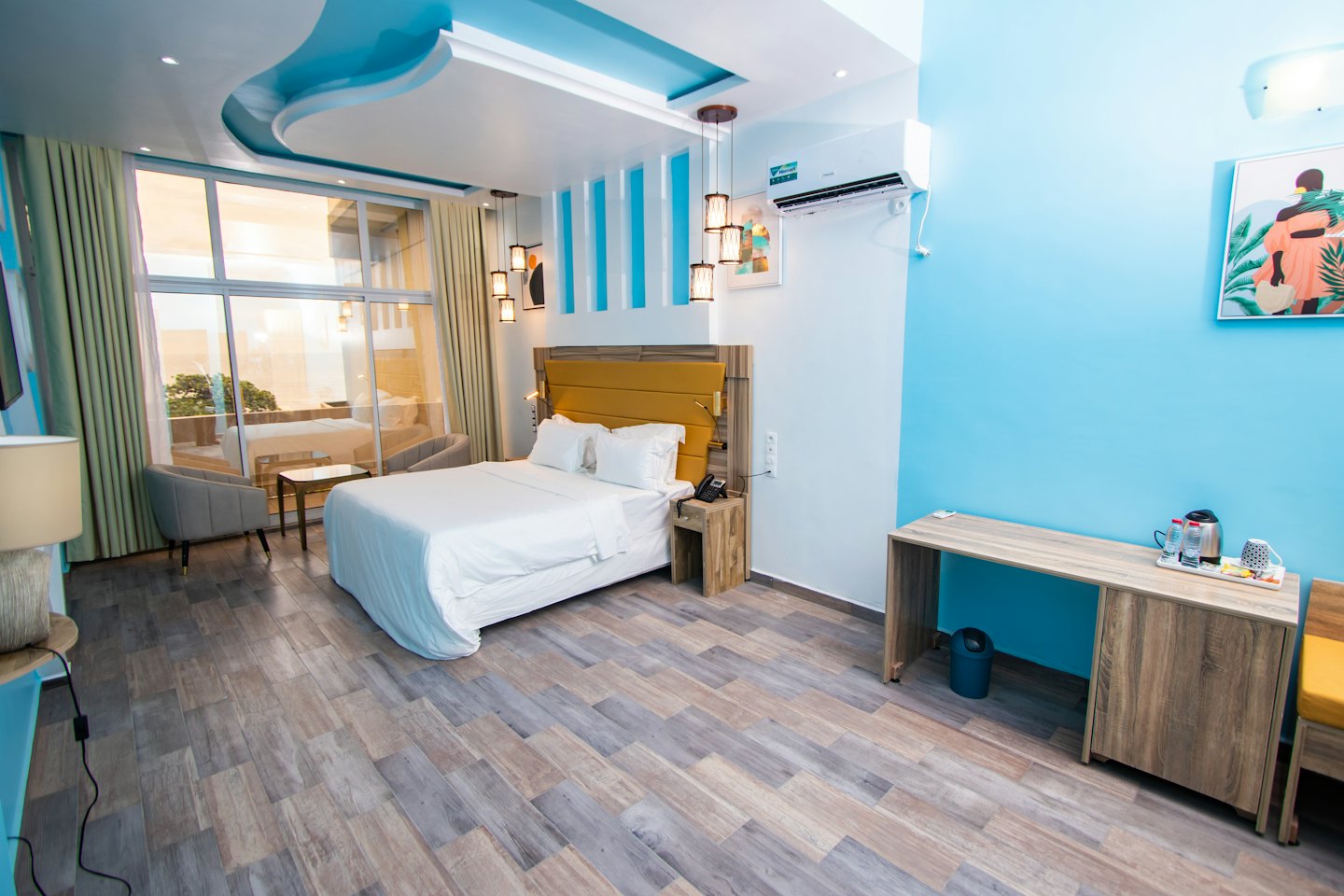 Hotel room with a queen bed and two grey armchairs.