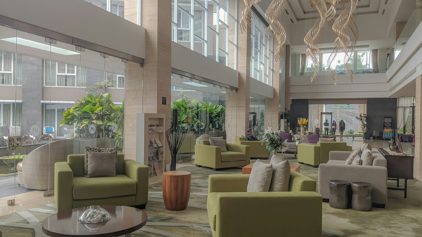 Modern hotel lobby with green chairs and sofas.