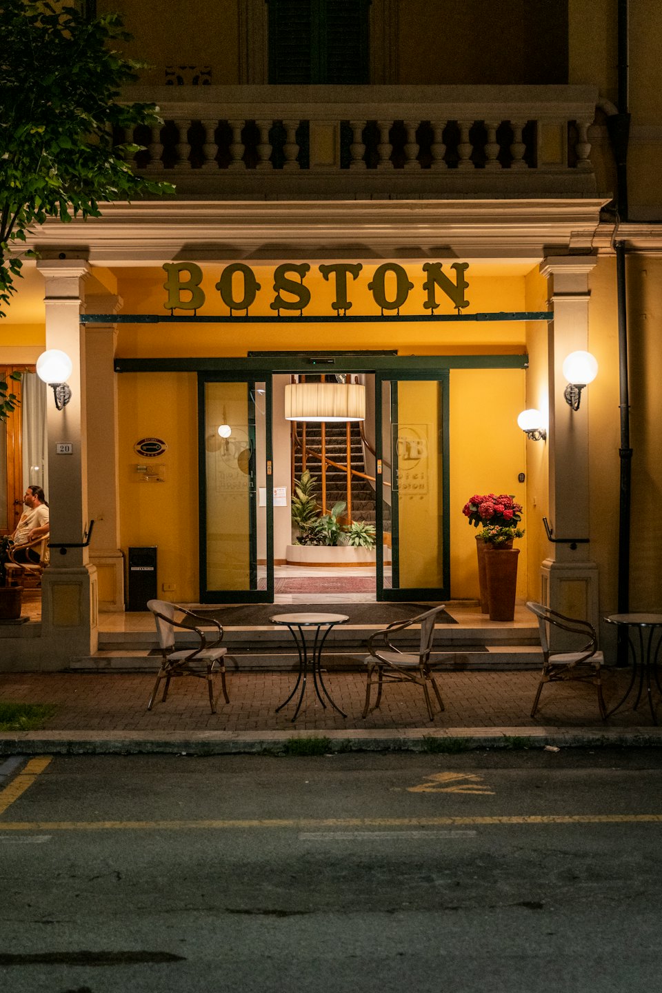 Yellow hotel entrance with outdoor tables on the sidewalk.