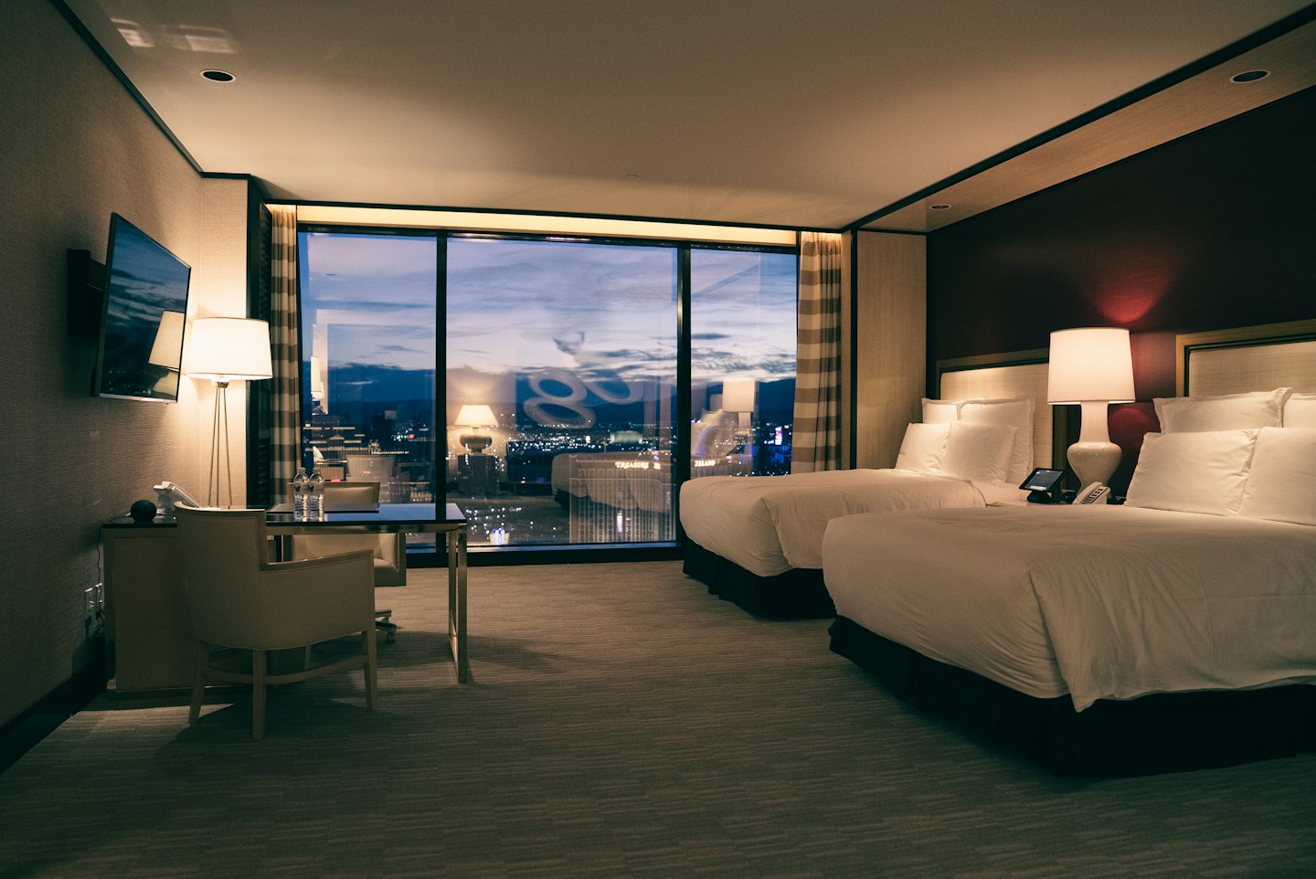 Modern hotel room with city views from floor-to-ceiling windows.